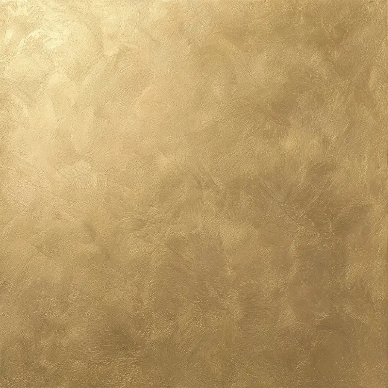 Macro-opname van handgetrokken metallic stuc in warm goud — fijne penseelhalen, zachte wolking en pearlescent shimmer