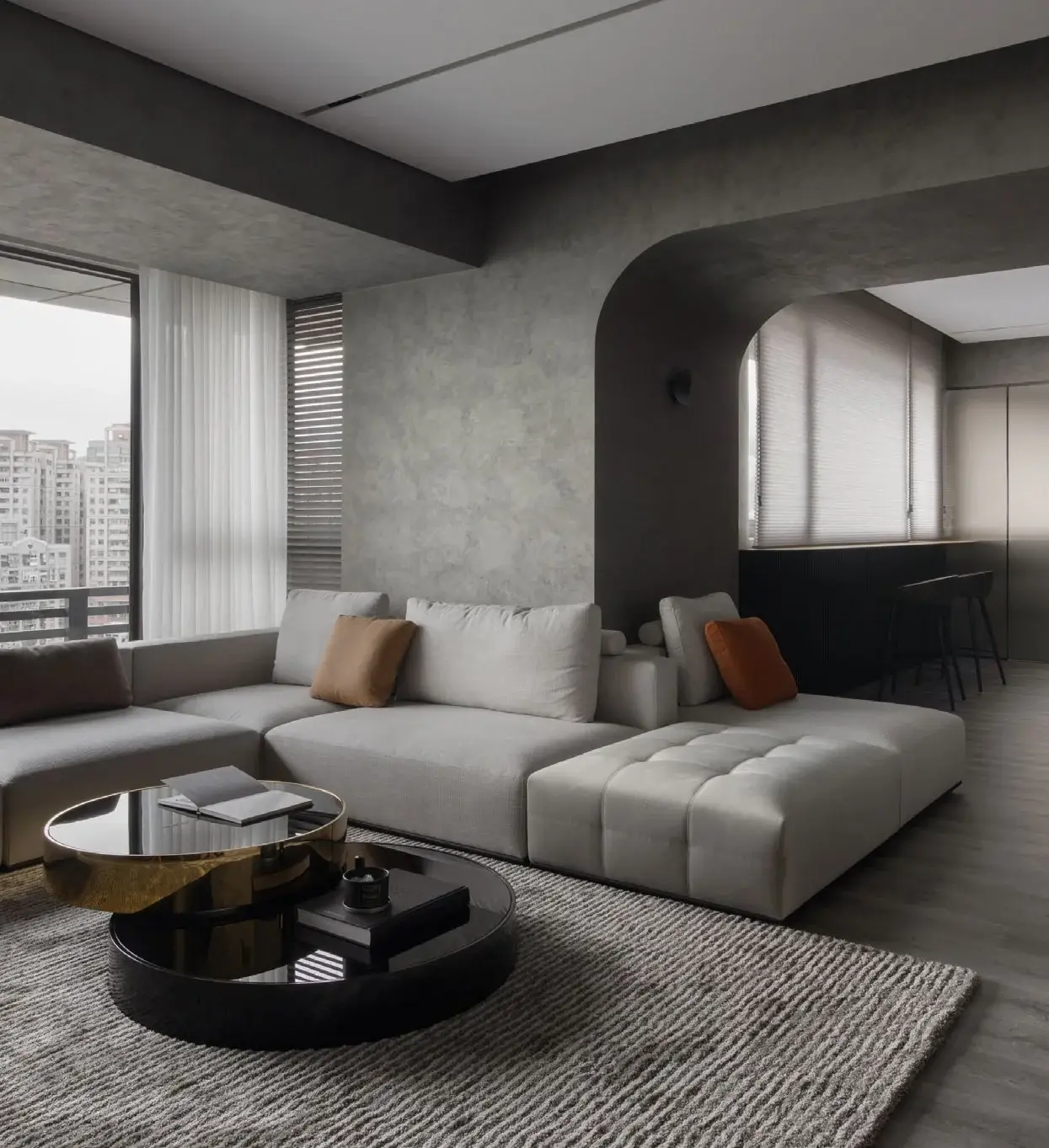 Woonkamer met grijze metallic kalkpleister wand, sectional bank en gouden salontafel