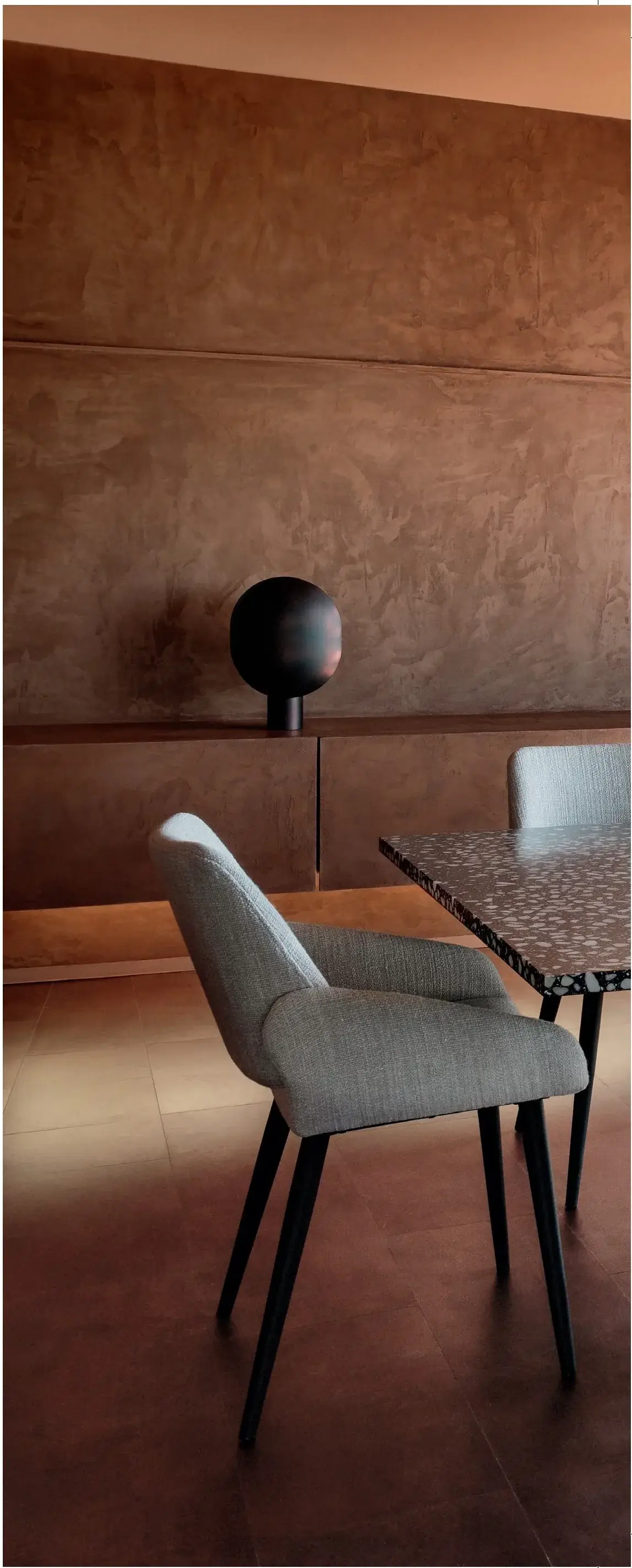 Eetkamer met warme terracotta kalkpleister wand en moderne stoel