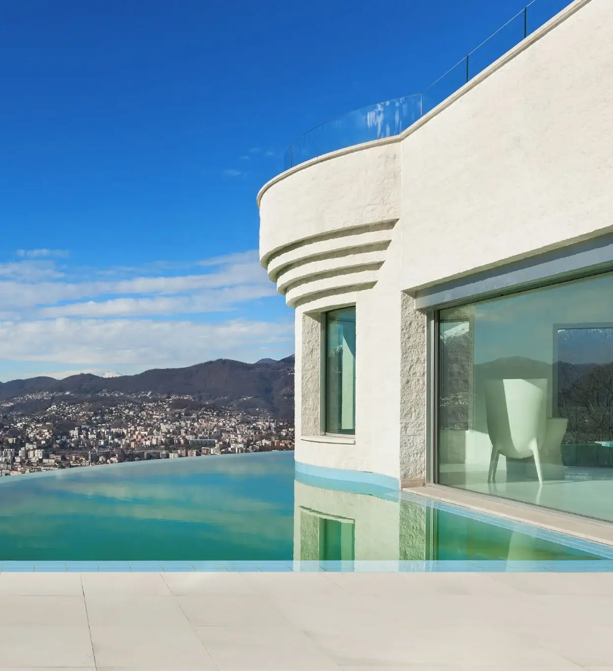Witte kalkpleister buitengevel van moderne villa met infinity pool en bergzicht