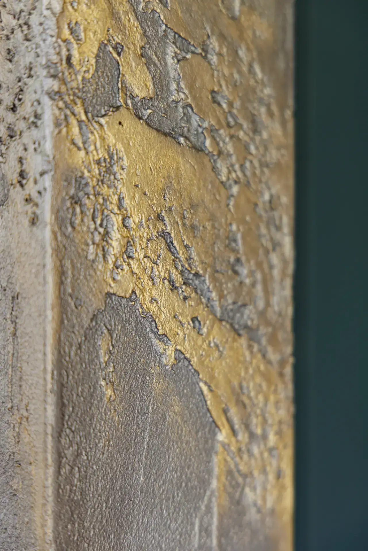 Metaalglans — Close-up van goud en zilvergrijs metallic over de ruwe, korrelige structuur van het reliëf. Foto: Wouter van der Sar.